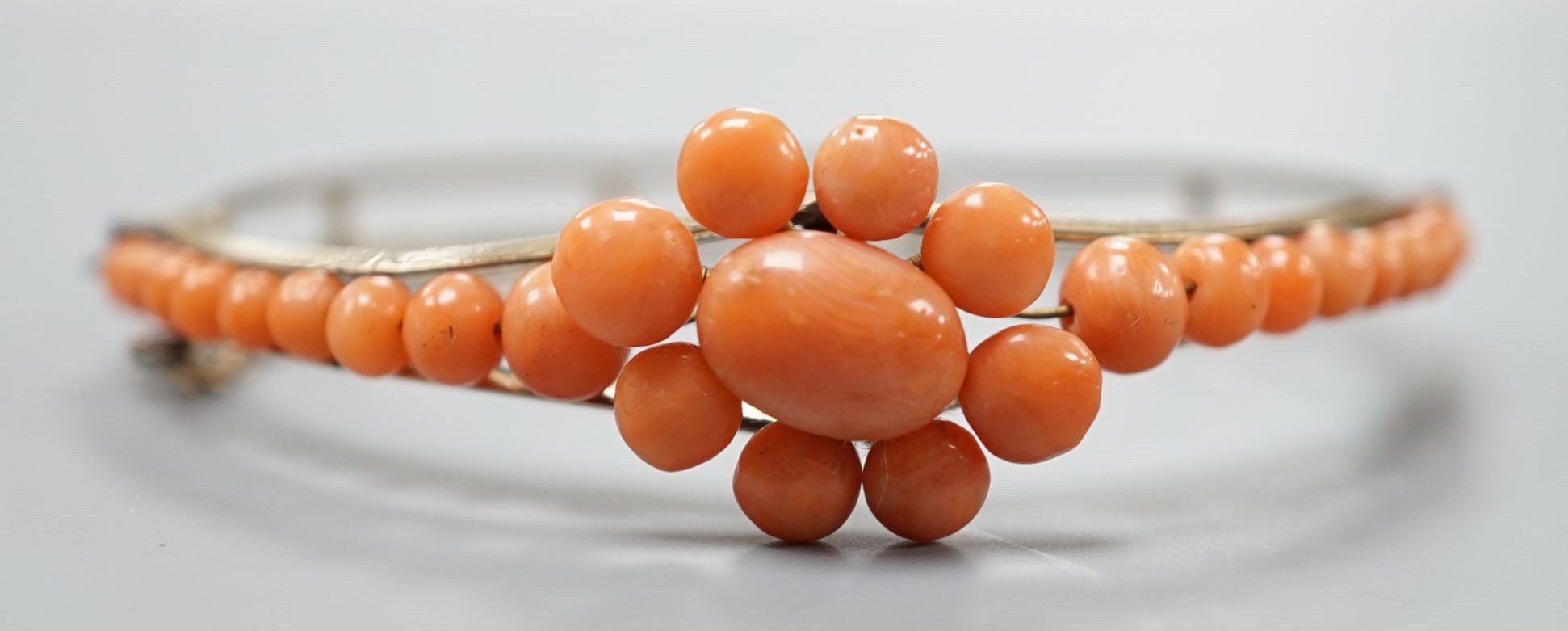 A gold plated and coral bead cluster set hinged bangle.